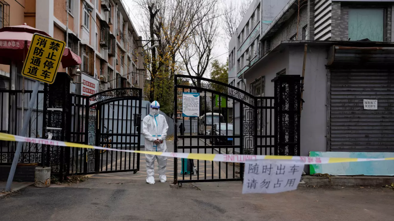 An epidemic-prevention worker in a protective suit stands guard at the gate of a residential compound as coronavirus disease (COVID-19) outbreaks continue in Beijing, China November 28, 2022. Reuters/Thomas Peter