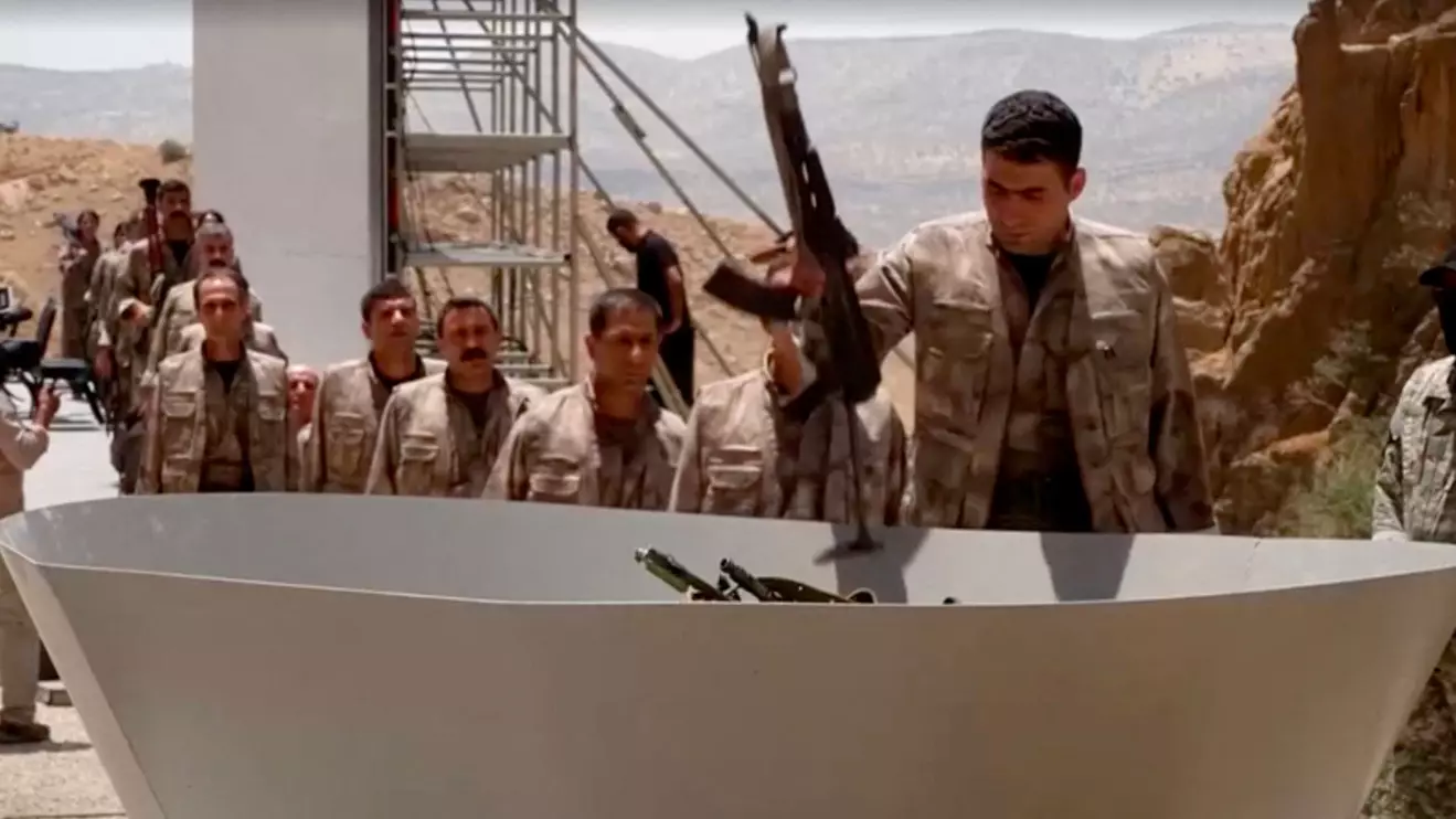 An armed PKK fighter places a weapon to be burnt during a disarming ceremony in Sulaimaniya, Iraq, July 11, 2025, in this screengrab obtained from a handout video © Kurdistan Workers Party 