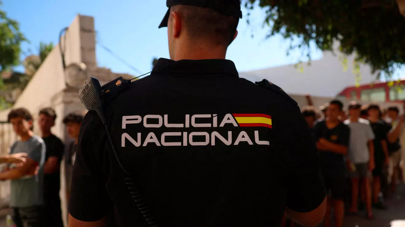 A police officer stands guard as migrant children queue outside a police station to be registered following mass crossings by migrants on foot and by sea from Morocco into Spanish territory, in Ceuta, Spain, August 6, 2026. Reuters/Violeta Santos Moura