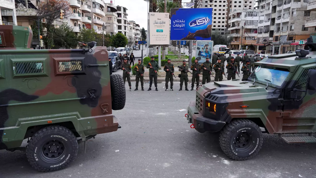 Members of the Syrian Security forces stand guard near military vehicles on the day people from the Alawite sect protest as they demand federalism and an end to what they say is the killing and violations against Alawites, in Latakia, Syria, December 28, 2025. Reuters/Karam al-Masri