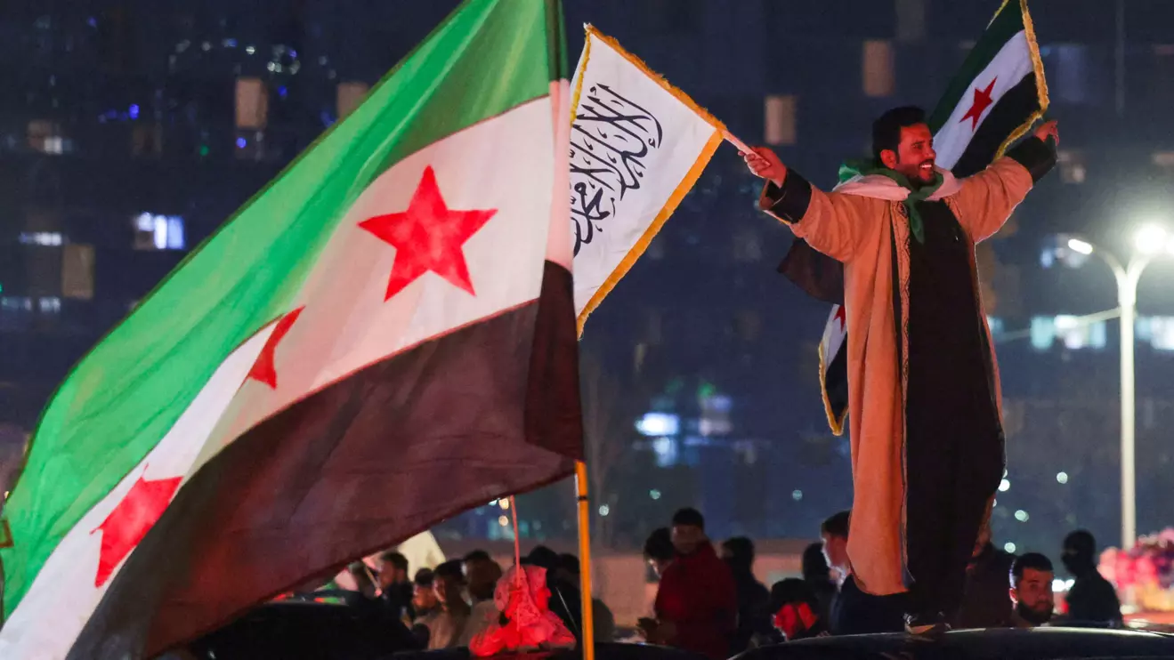 A person holds flags as people celebrate after the Kurdish-led and U.S.-backed Syrian Democratic Forces (SDF), which controls much of Syria's oil-rich northeast, has signed a deal agreeing to integrate into Syria's new state institutions, the Syrian presidency said on Monday, in Damascus, Syria March 11, 2025. Reuters/Khalil Ashawi