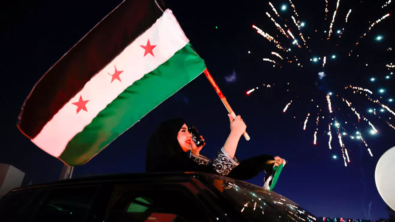 A woman holds up the flag adopted by the new Syrian rulers, as people celebrate after fighters of the ruling Syrian body ousted Syria's Bashar al-Assad, in the Damascus old city, Syria, December 13, 2024. Reuters/Ammar Awad