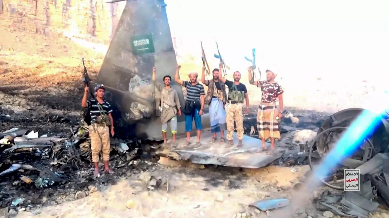 Houthi fighters stand in front of what they say is a downed Saudi jet, at a location given as Yemen, in this still image from a handout video released on September 16, 2026. Houthi Military Media/ Handout via Reuters