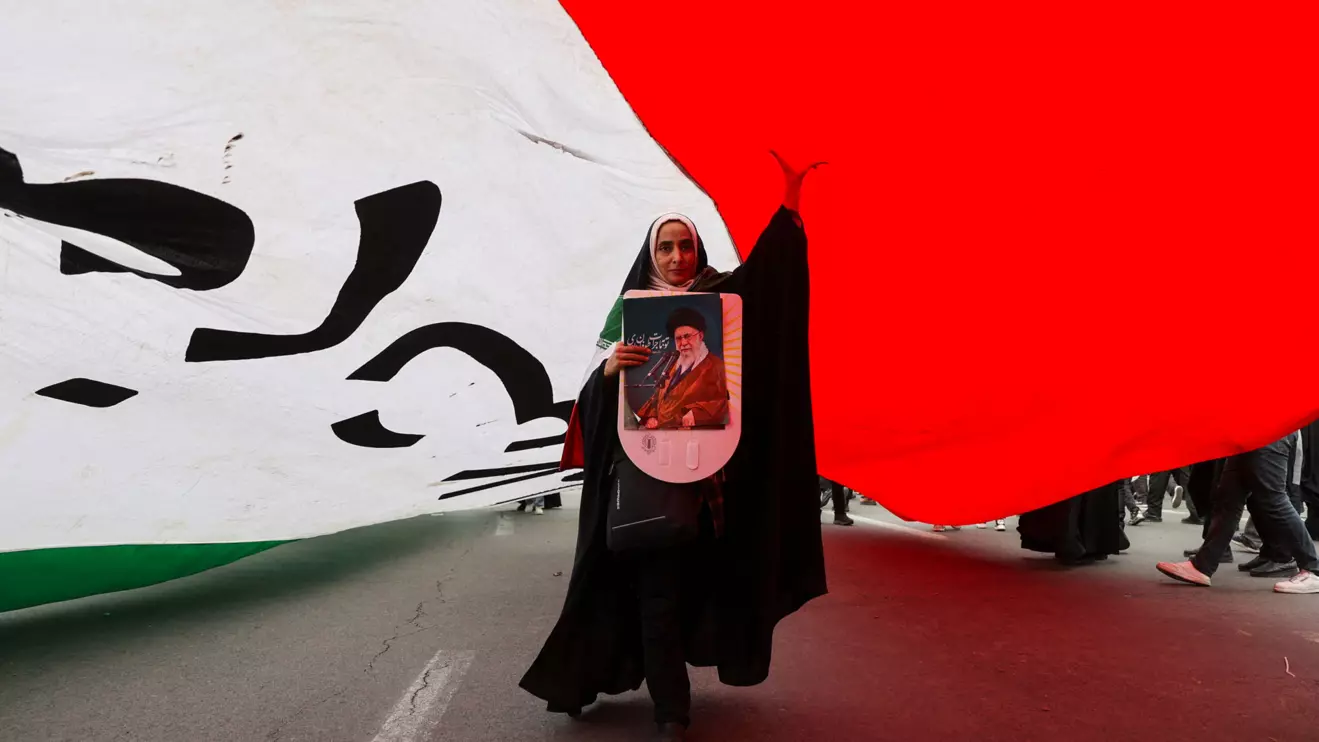 An Iranian woman holding a poster depicting Iran's Supreme Leader Ayatollah Ali Khamenei walks under a large flag during the 47th anniversary of the Islamic Revolution in Tehran, Iran February 11, 2026. Majid Asgaripour/WANA (West Asia News Agency) via Reuters