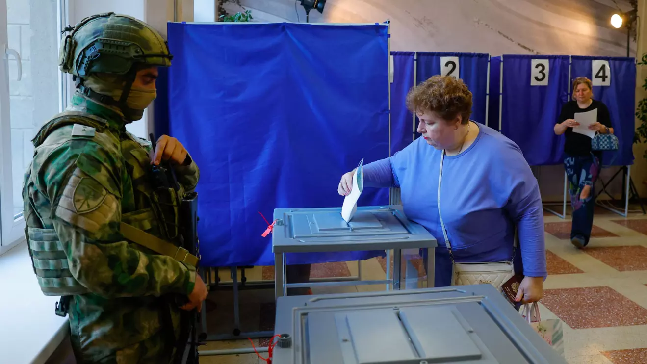 A woman casts her ballot next to a serviceman securing a poling station during Russia's parliamentary elections, in the course of Russia-Ukraine conflict in Donetsk, Russian-controlled Ukraine, September 18, 2026. Reuters/Alexander Ermochenko