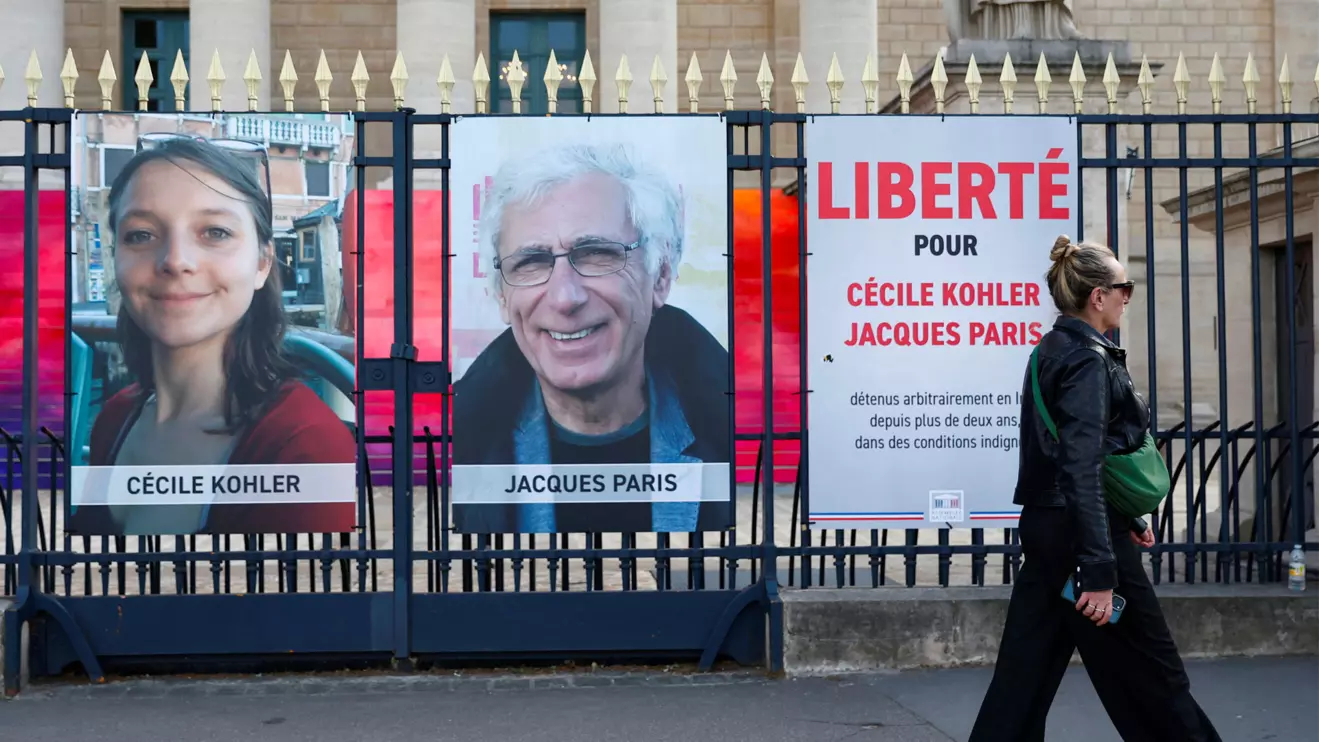 A woman walks past posters with the portraits of Cecile Kohler and Jacques Paris, two French citizens held in Iran, on the day of support rallies to mark their three-year detention and to demand their release, in front of the National Assembly in Paris, France, May 7, 2025. The slogan reads "Freedom for Cecile Kohler and Jacques Paris". Reuters/Abdul Saboor