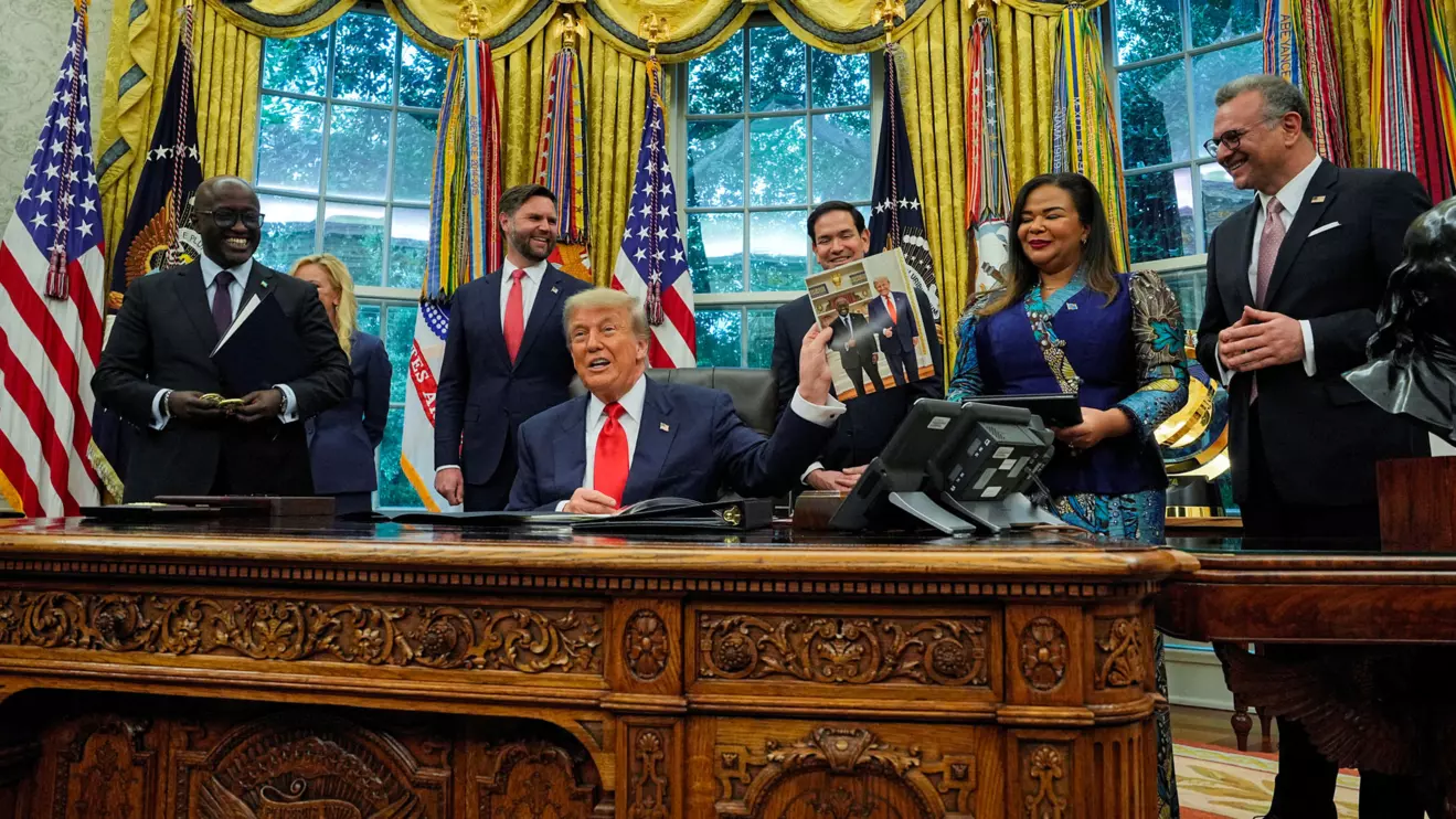 U.S. President Donald Trump holds a picture of himself with Rwanda's Foreign Minister Olivier Nduhungirehe, during a meeting with Foreign Minister Nduhungirehe and the Democratic Republic of the Congo's Foreign Minister Therese Kayikwamba Wagner in the Oval Office at the White House in Washington, D.C., June 27, 2025. Reuters/Ken Cedeno