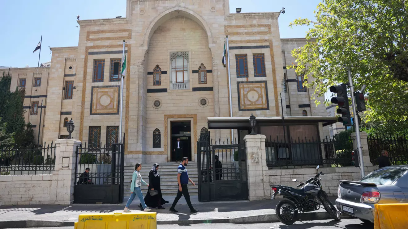 A group of civilians walk past the main gate of the Syrian parliament building, in Damascus, Syria September 3, 2025. Reuters/Khalil Ashawi