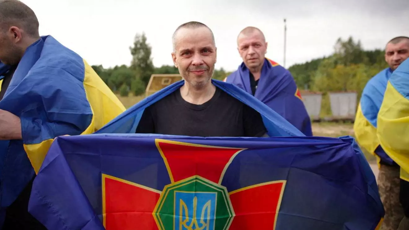 A Ukrainian prisoner of war (POW), wrapped in an Ukrainian flag, poses for a photo after a swap, amid Russia's attack on Ukraine, at an unknown location in Ukraine, in this handout picture released August 24, 2025. Ukraine's Interior Minister Ihor Klymenko via Telegram