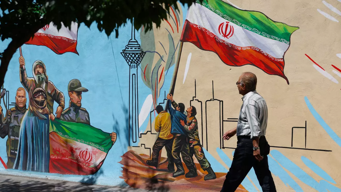 An Iranian man walks next to a mural on a street in Tehran, Iran, May 11, 2026. Majid Asgaripour/WANA (West Asia News Agency) via Reuters