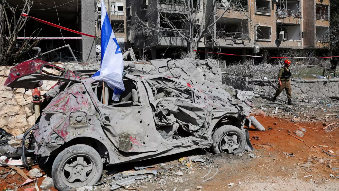 A rescuer walks next to a damaged vehicle at an impact site following missile attack from Iran on Israel, in Ramat Gan, Israel, June 14, 2025. Reuters/Ronen Zvulun