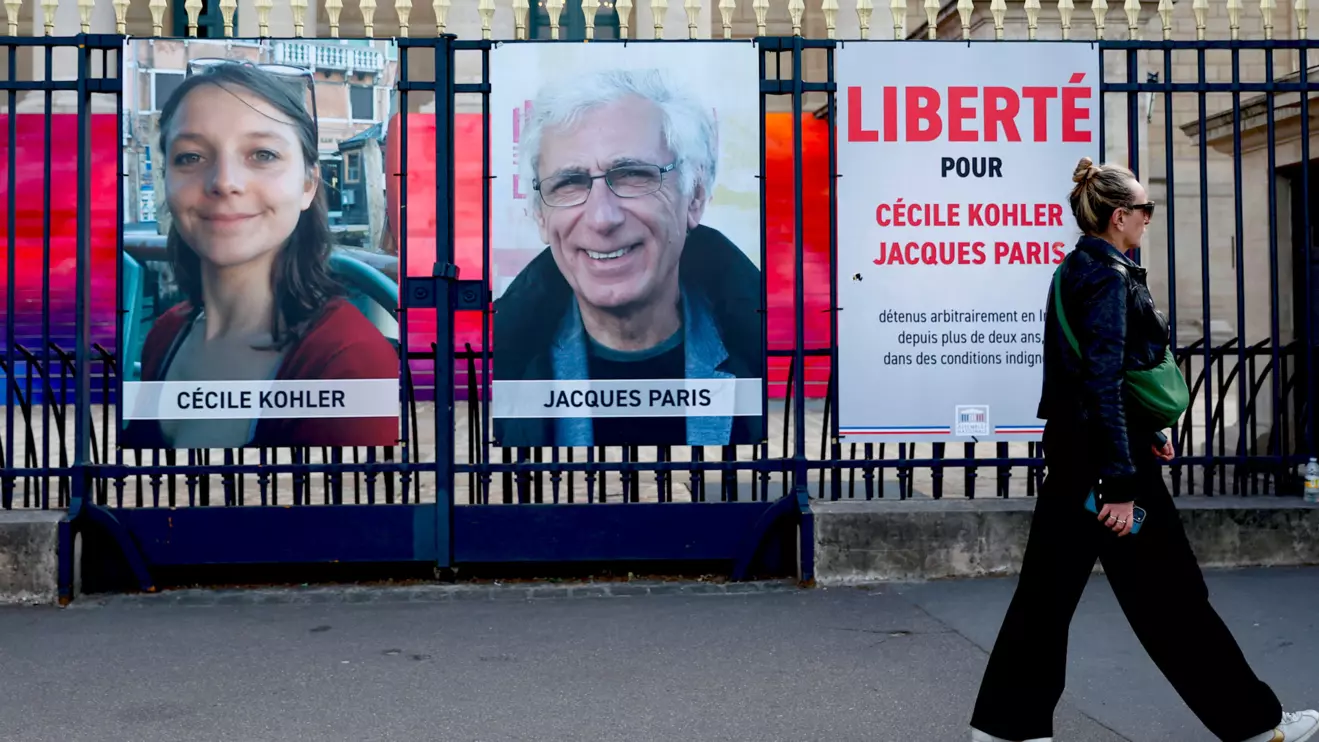 A woman walks past posters with the portraits of Cecile Kohler and Jacques Paris, two French citizens held in Iran, on the day of support rallies to mark their three-year detention and to demand their release, in front of the National Assembly in Paris, France, May 7, 2025. The slogan reads "Freedom for Cecile Kohler and Jacques Paris". Reuters/Abdul Saboor
