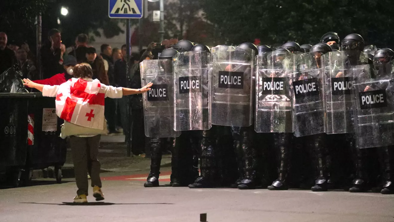 A protester wearing a Georgian flag walks towards police officers blocking the street during an opposition rally on the day of local elections in Tbilisi, Georgia October 4, 2025. Reuters/Irakli Gedenidze
