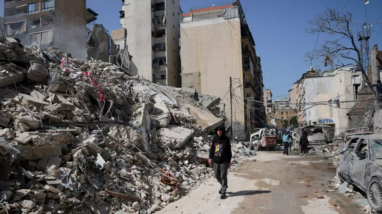 A person walks past debris at the site of an Israeli strike, following an escalation between Hezbollah and Israel amid the U.S.-Israeli conflict with Iran, Zuqaq al-Blat district in central Beirut, Lebanon, March 18, 2026. Reuters/Khalil Ashawi