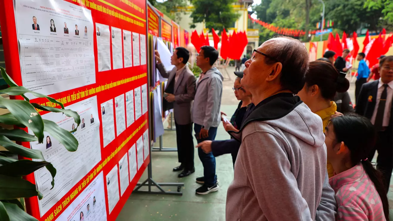 People look at a board with information about candidates outside a polling station during a parliamentary election, in Hanoi, Vietnam, March 15, 2026. Reuters/Thinh Nguyen