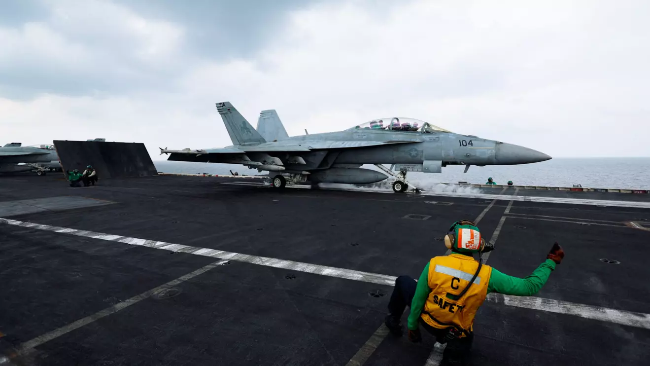 A flight operating crew member signals a F/A-18E Super Hornet fighter jet on the flight deck of the USS Dwight D. Eisenhower (CVN 69) aircraft carrier in Southern Red Sea, Middle East, February 13, 2024. Reuters/Hamad I Mohammed