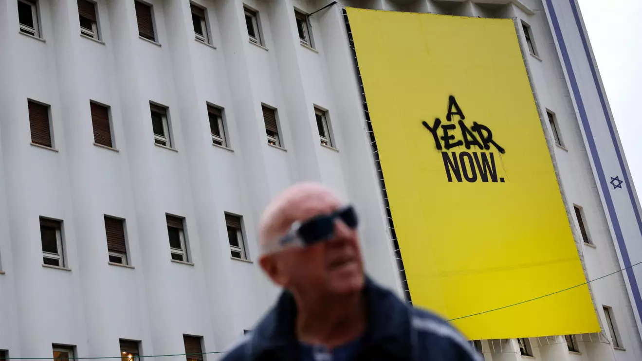 A man walks past a banner that was made for the one-year anniversary of the deadly October 7, 2023 attack by Hamas, in Tel Aviv, Israel, December 11, 2024. ReutersS/Stoyan Nenov