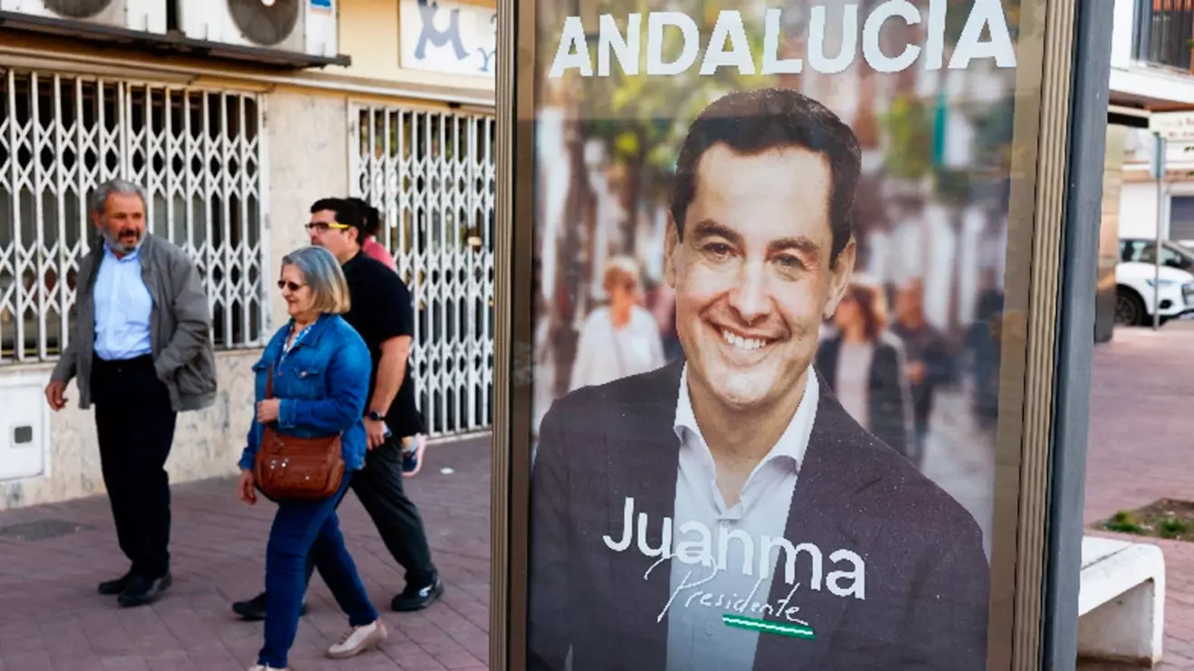 People walk past an electoral poster of Andalusian regional president and People's Party (PP) candidate, Juanma Moreno Bonilla, during the Andalusian regional elections in Ronda, Spain May 17, 2026, Reuters/Jon Nazca