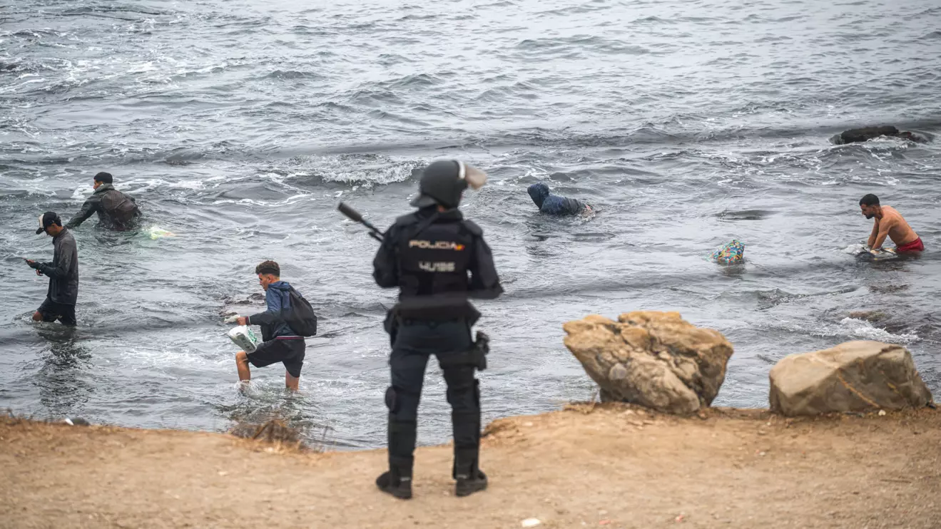 Migrants swim at El Trampolin beach heading to the nearby El Guano, an immigrants' settlement, as Police clear up an encampment of migrants at El Trampolin beach in the Spanish enclave of Ceuta, in Ceuta, Spain, October 4, 2026. Reuters/Marcos Moreno