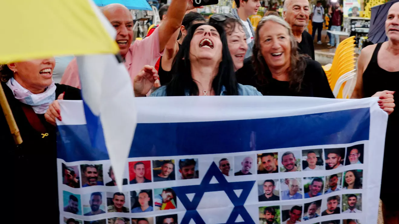 Einav Zangauker, the mother of hostage Matan Zangauker, reacts holding an Israeli flag with photos of hostages, after U.S. President Donald Trump announced that Israel and Hamas agreed on the first phase of a Gaza ceasefire, at the "Hostages square", in Tel Aviv, Israel, October 9, 2025. Reuters/Ronen Zvulun