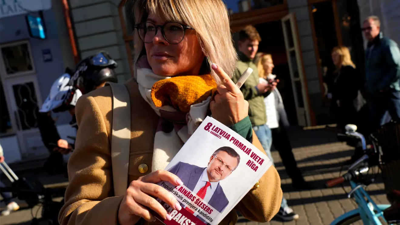 A woman holds an election campaign leaflet of the "Latvia First" party with a picture of the party's leader, Ainars Slesers, before the general election in Riga, Latvia, September 27, 2026. Reuters/Ints Kalnins