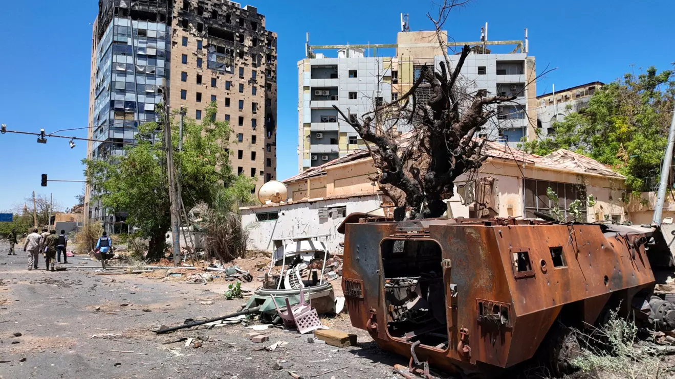 Members of army walks near a destroyed military vehicle and bombed buildings, as Sudan's army retakes ground and some displaced residents return to ravaged capital in the state of Khartoum Sudan March 26, 2025. Reuters/El Tayeb Siddig