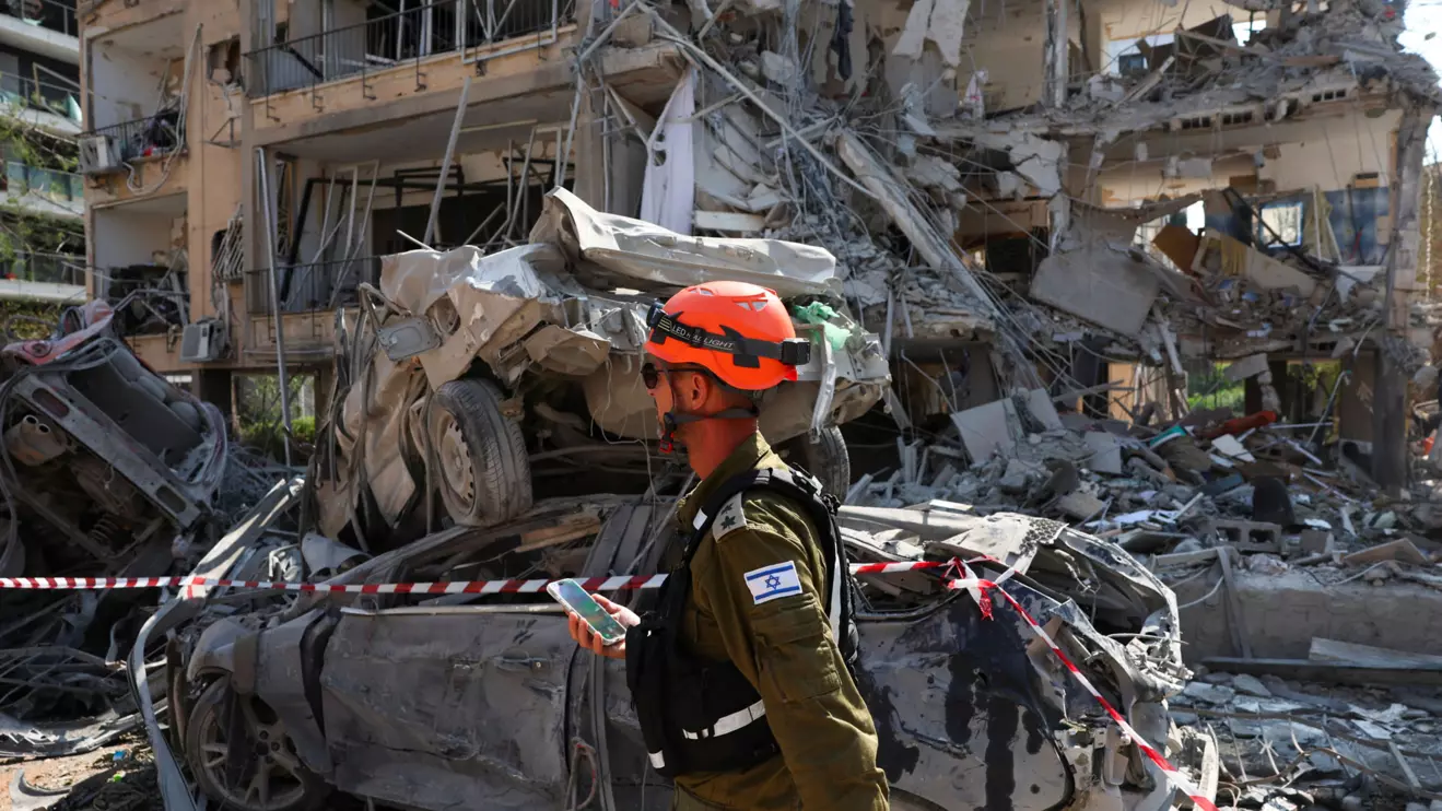 Rescue personnel walks past damaged vehicles at an impact site following missile attack from Iran on Israel, in Ramat Gan, Israel, June 14, 2025. Reuters/Ronen Zvulun