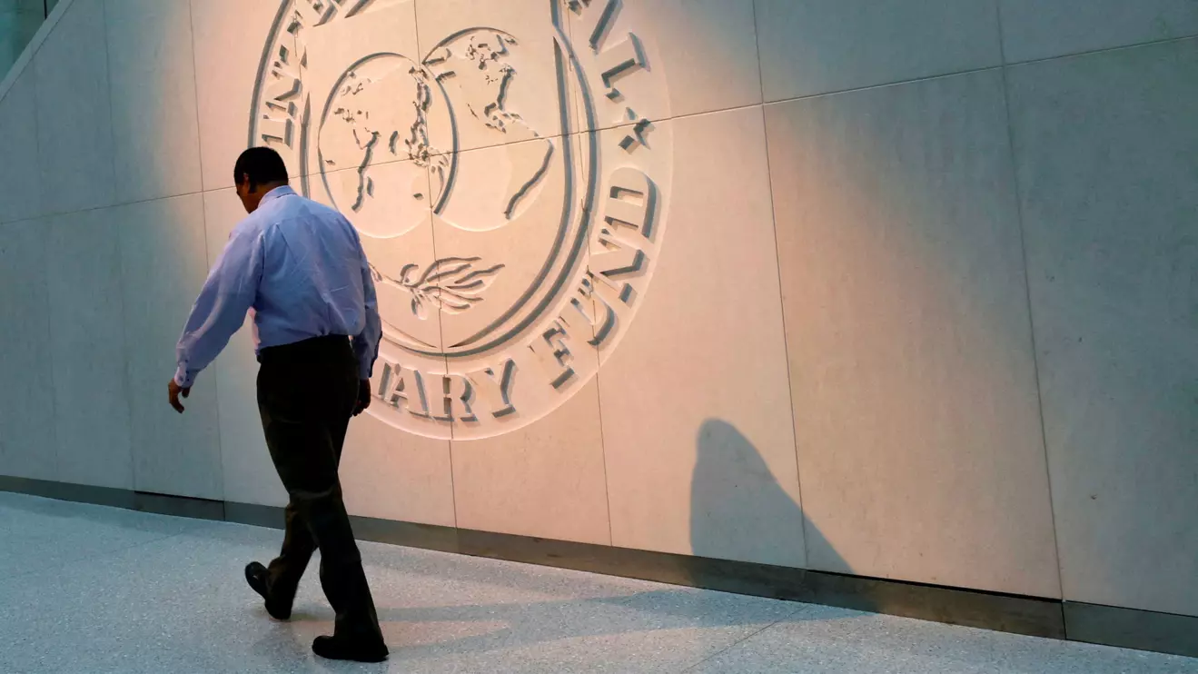 A man walks past the International Monetary Fund (IMF) logo at its headquarters in Washington, Reuters/Yuri Gripas
