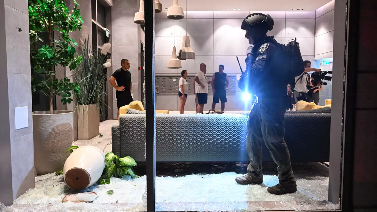An Israeli police officer inspects the damage to a residential building caused by a rocket fired towards Israel from Lebanon, amid cross-border hostilities between Hezbollah and Israel, in Haifa, Israel, October 7, 2024. Reuters/Rami Shlush