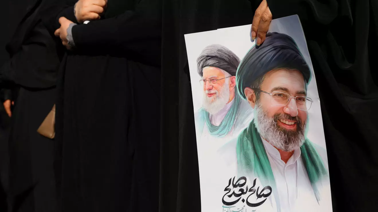 A woman holds an image of Iran's new supreme leader, Mojtaba Khamenei, alongside late Iranian Supreme Leader Ayatollah Ali Khamenei, during a funeral ceremony for the Iranian military commanders who were killed in strikes, amid the U.S.-Israeli conflict with Iran, in Tehran, Iran, March 11, 2026. Majid Asgaripour/WANA (West Asia News Agency) via Reuters 