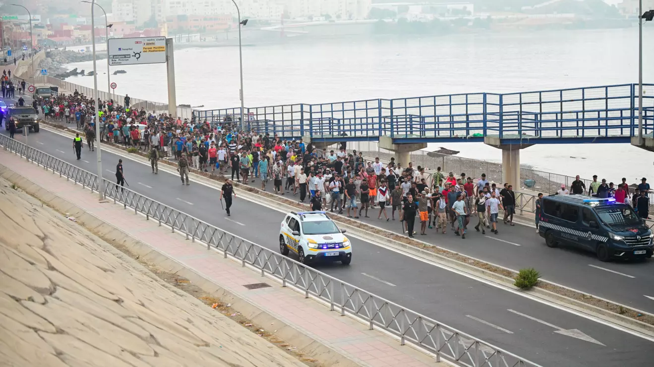 Police officers and Spanish soldiers escort a big group of migrants to the border to take them out of Spain, after mass crossings of migrants on foot and by sea from Morocco into Spanish territory, in Ceuta, Spain, August 1, 2026. Reuters/Fabian Bimm