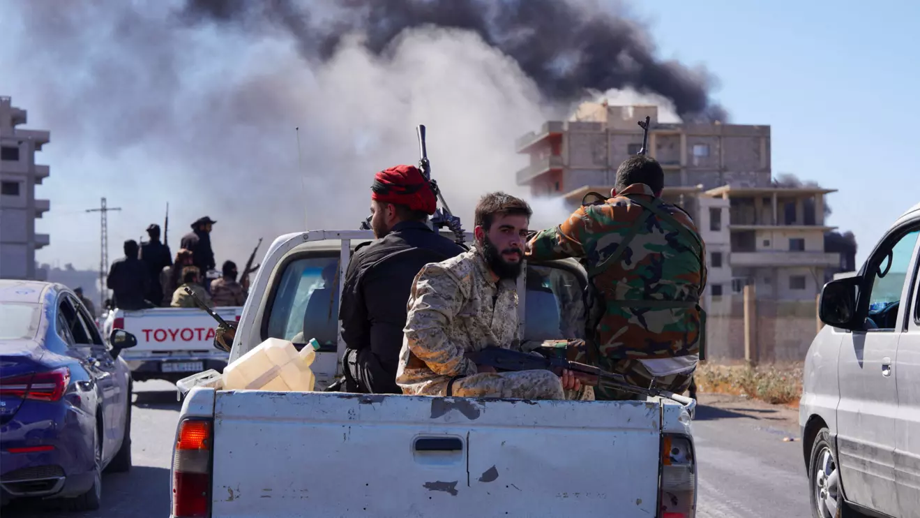 Smoke rises while Syrian security forces sit in the back of a truck as Syrian troops entered the predominantly Druze city of Sweida on Tuesday following two days of clashes, in Sweida, Syria July 15, 2025. Reuters/Karam al-Masri