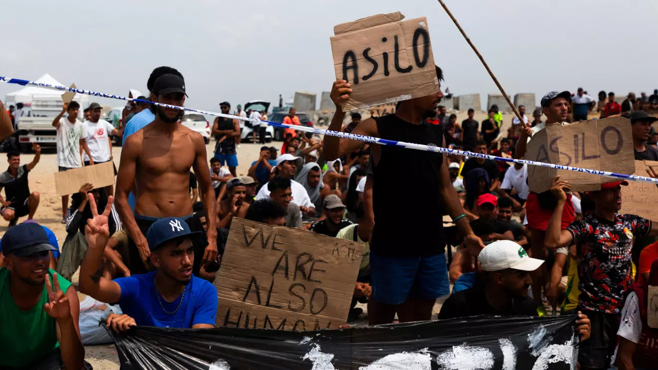 Migrants hold signs reading "Asilo," Spanish for "asylum," as they gather in Ceuta, Spain, August 16, 2026. Reuters/Maria Alejandra Cardona