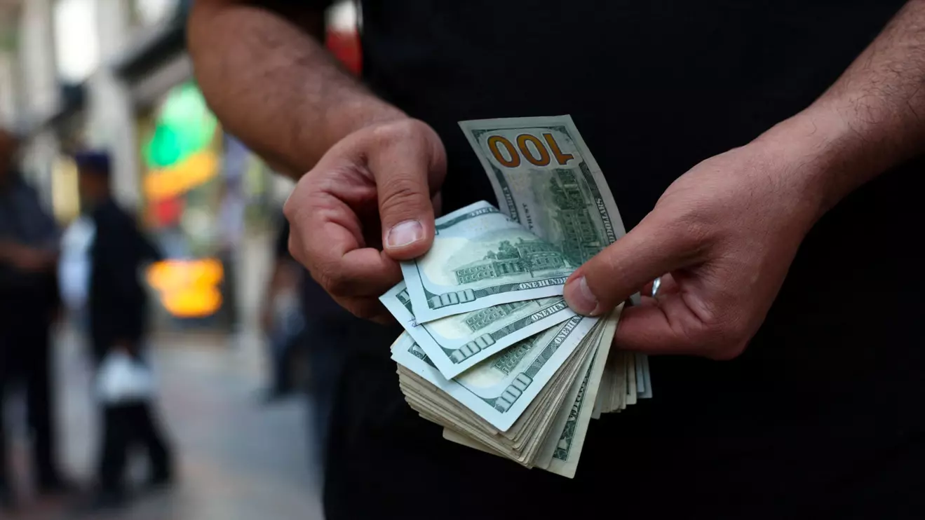 A currency dealer holds one-hundred-dollar bills in Tehran, Iran, May 2, 2026. Majid Asgaripour/WANA (West Asia News Agency) via Reuters