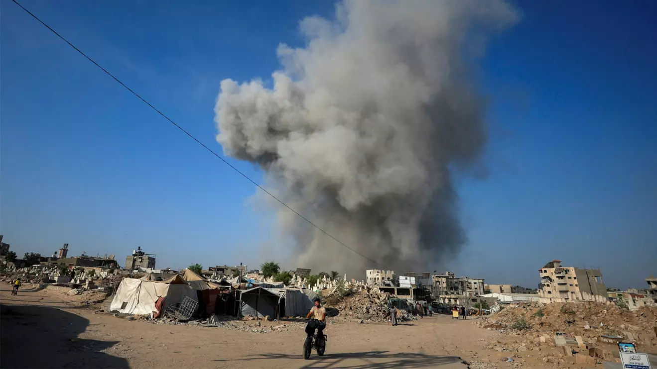 A Palestinian man rides a bike as smoke rises following an Israeli strike, in Gaza City, August 24, 2025. Reuters/Dawoud Abu Alkas