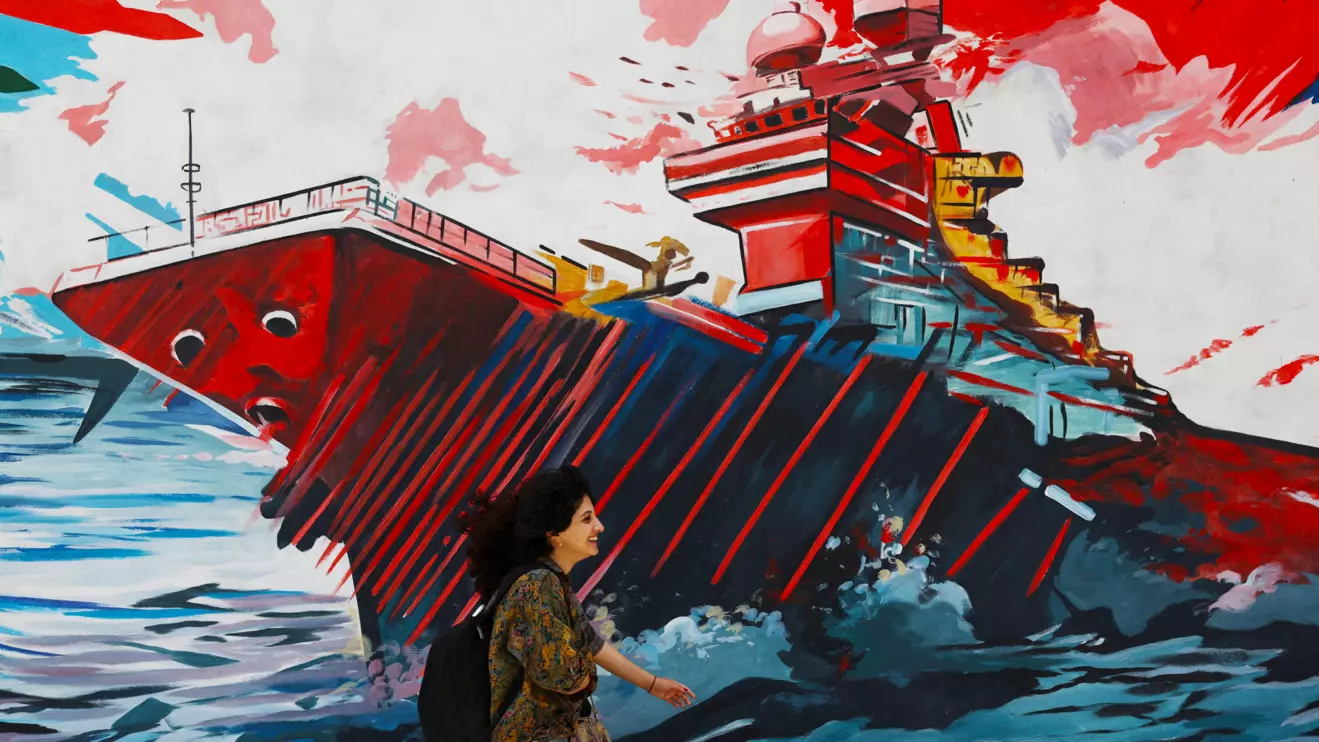 An Iranian woman walks next to a mural on a street in Tehran, Iran, May 6, 2026. Majid Asgaripour/WANA (West Asia News Agency) via Reuters