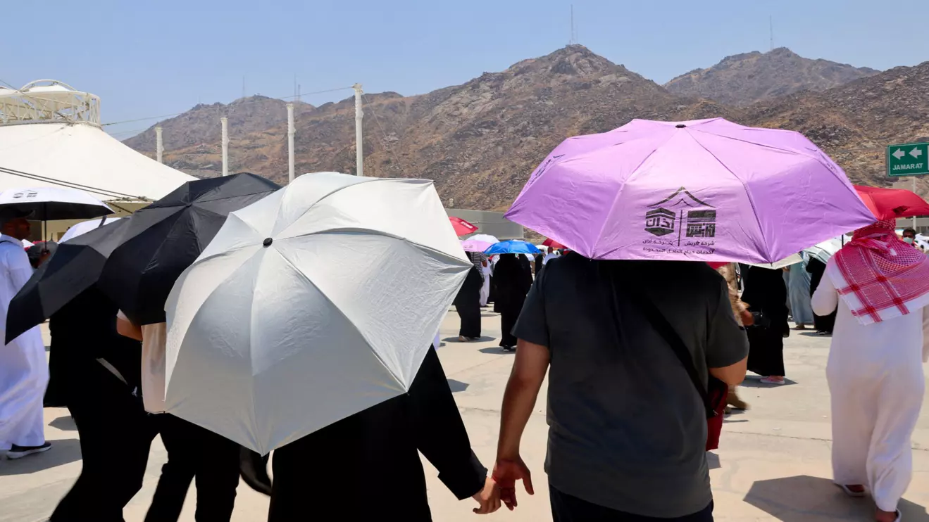 Muslim pilgrims hold hands as they walk with umbrellas to the site where people take part in the Satan stoning ritual, during the annual haj pilgrimage in Mina, Saudi Arabia June 18, 2024. Reuters/Saleh Salem
