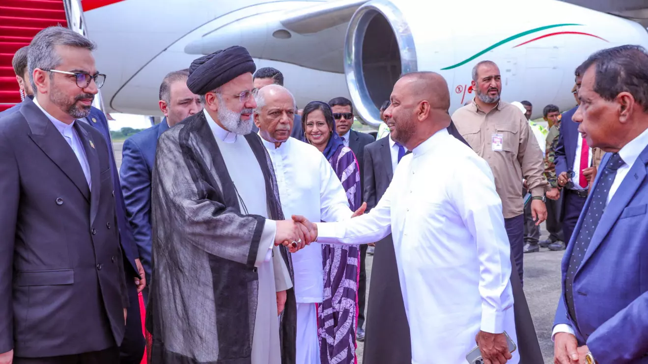 Iran's President Ebrahim Raisi shakes hands with Sri Lanka's Agriculture Minister Mahinda Amaraweera as Prime Minister Dinesh Gunawardena looks on, upon Raisi's arrival at Mattala Rajapaksa International Airport, Sri Lanka, April 24, 2024. President Media/Handout via Reuters