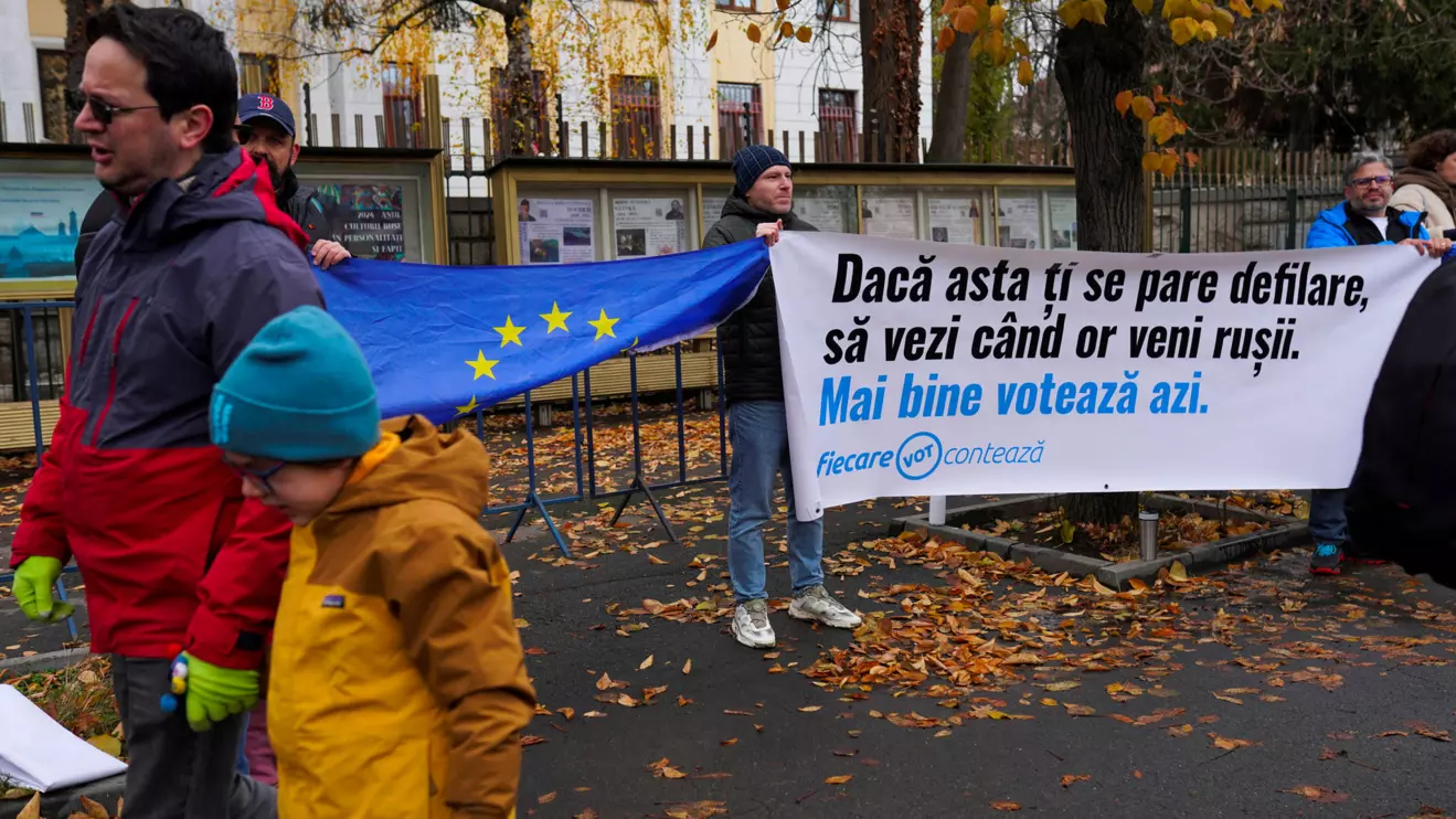 A man and a child walk past a banner reading: "If you think this is a parade, wait to see when the Russians will come. Better go vote today", in front of the Russian embassy, on the day of parliamentary elections, in Bucharest, Romania, December 1, 2024. Reuters/Andreea Campeanu