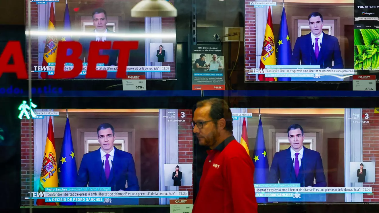 A person walks next to TVs broadcasting the statement by Spain's Prime Minister Pedro Sanchez, in El Masnou, north of Barcelona, April 29, 2024. Reuters/Albert Gea