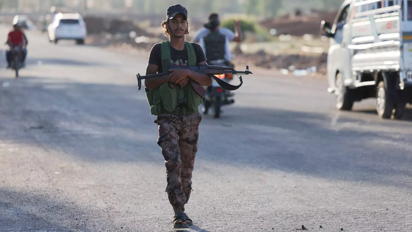An armed Syrian Bedouin fighter walks along a road, as they launch a new offensive in Syria's Sweida province against Druze fighters, Reuters/Khalil Ashawi