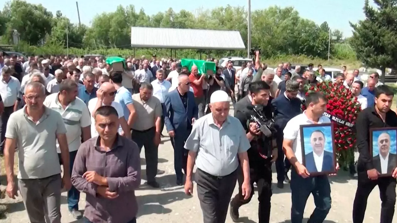 People followed by mourners carry the coffins of Azerbaijani brothers Huseyn and Ziyaddin Safarov, who died in Russian police custody, to a cemetery in Hacibedelli, Azerbaijan, July 1, 2025, in this still image from video, Reuters