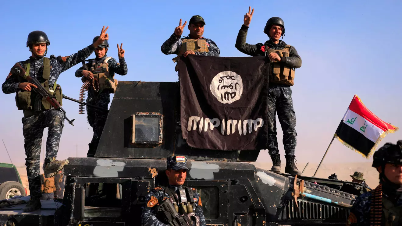 Federal police members pose with an Islamic State (IS) flag along a street of Albu Saif which was recaptured from Islamic State, south of Mosul, Iraq, February 22, 2017. Reuters/Zohra Bensemra