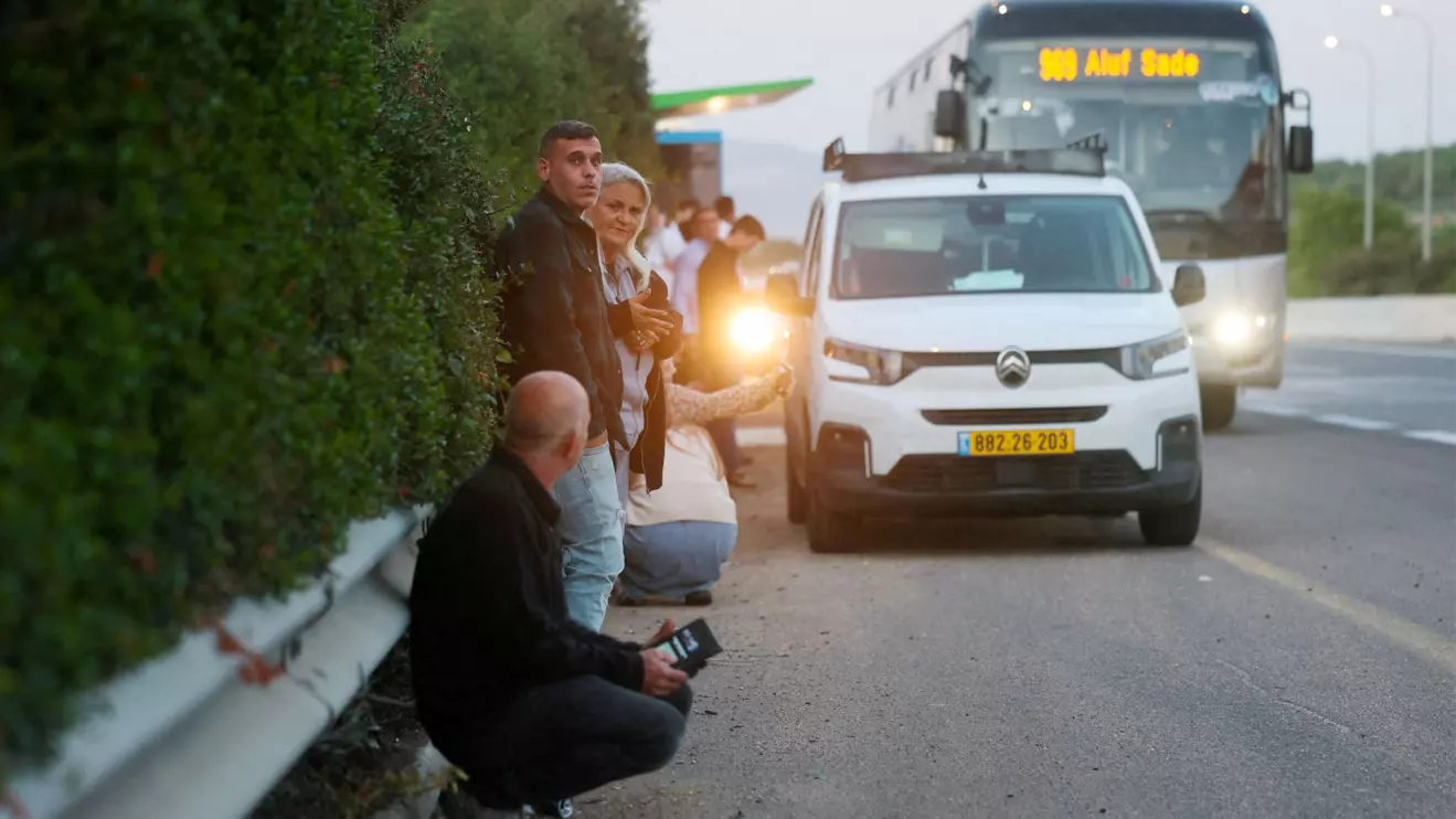 People gather on the side of a road seeking protection as a rocket volley from Iran flies overhead, amid the U.S.-Israeli conflict with Iran, in northern Israel, Reuters/Ammar Awad