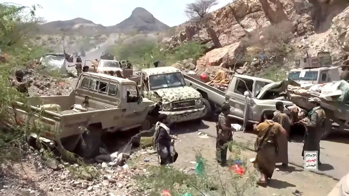 Fighters gather near damaged military vehicles in the aftermath of what a Houthi-owned TV network says are strikes on pro-government forces at an unknown location in Yemen, in this still image taken from video released September 12, 2026. Al-Masirah TV
