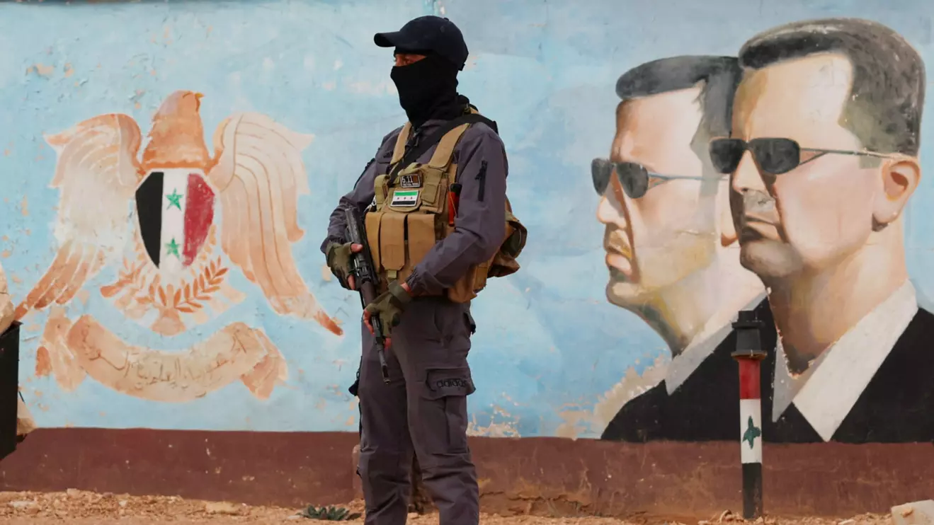 A member of the former rebel group Hayat Tahrir al-Sham stands guard near an image of Syria's Bashar al-Assad at the fourth division headquarters in Damascus, Syria, January 23, 2025 Reuters/Yamam Al Shaar