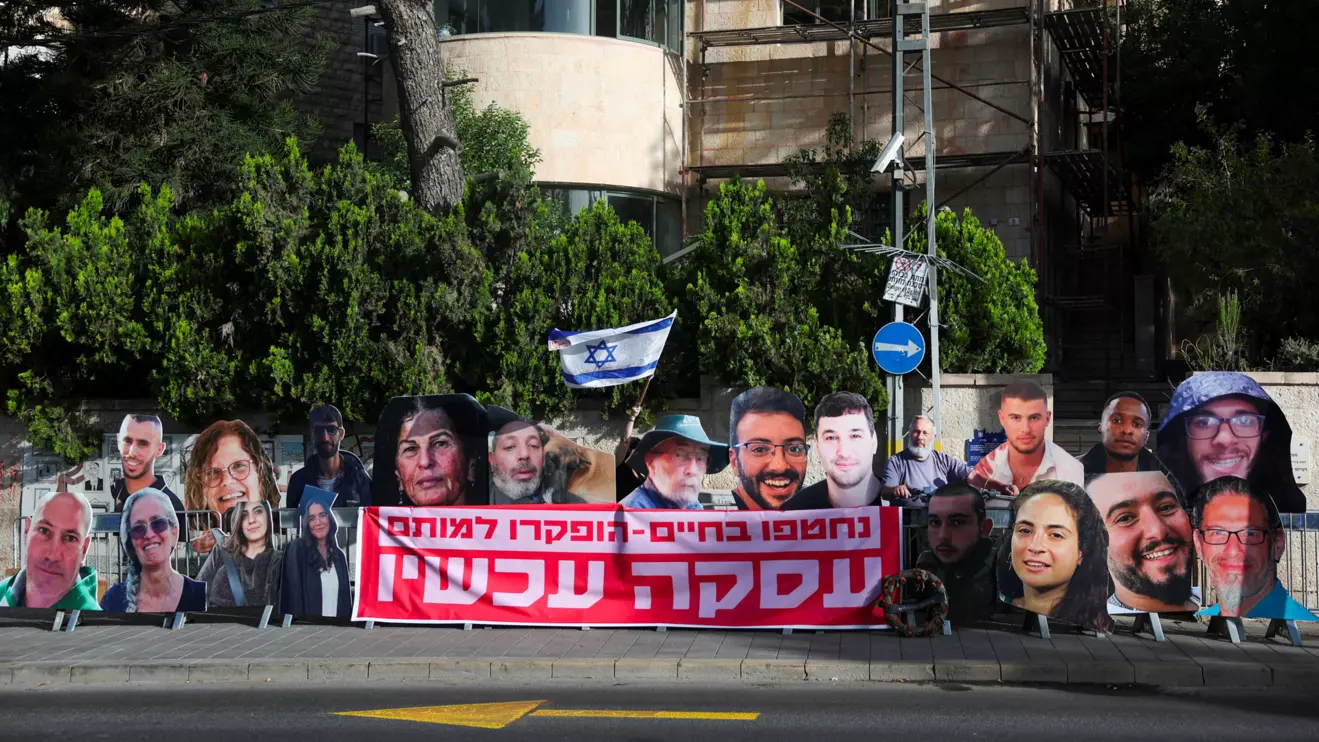 A woman holds an Israeli flag near the posters of hostages, killed during the deadly October 7 attack by Palestinian Islamist group Hamas or while being held hostage in Gaza, outside the Prime Minister's residence in Jerusalem May 23, 2024. Reuters/Ronen Zvulun