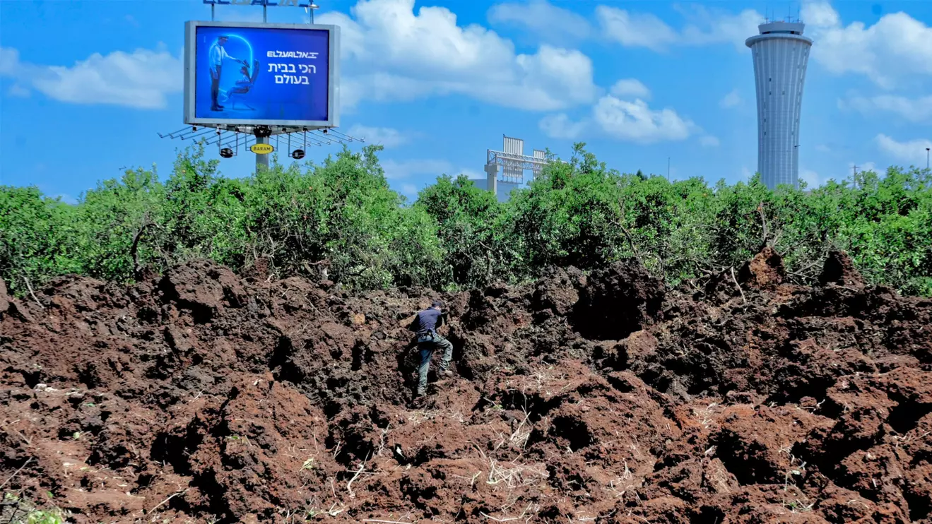 An Israeli police officer investigates a crater at the site of a missile attack, launched from Yemen, near Ben Gurion Airport, in Tel Aviv, Israel May 4, 2025. Reuters/Avshalom Sassoni