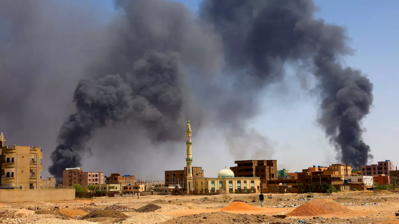 A man walks while smoke rises above buildings after aerial bombardment, during clashes between the paramilitary Rapid Support Forces and the army in Khartoum North, Sudan, May 1, 2023. Reuters/Mohamed Nureldin Abdallah