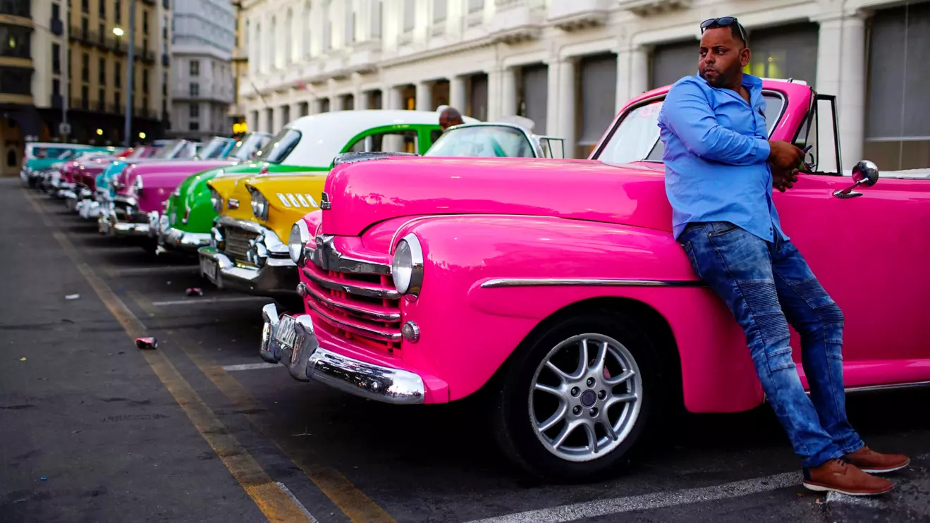 Driver Giovani Bernati waits for tourists beside vintage cars used as taxi in Havana, Reuters/Alexandre Meneghini